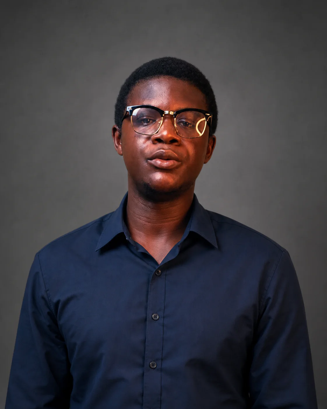 Caleb Oke wearing a navy shirt against a grey studio background